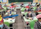 Povinné odstupy ve školách jako ochrana před koronavirem: Školáci v čínském Chang-čou nosí speciální čepice s metrovými tyčemi